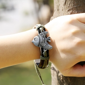 Bracelet en cuir tissé à la main avec pendentif poisson dans un cadre naturel chic