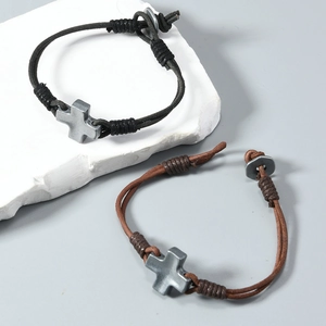 Détail de bracelets croix en cuir tressé avec cordons réglables en noir et marron
