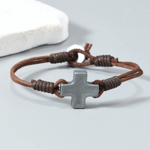 Détail du bracelet en cuir tressé marron fait main avec breloque croix vintage