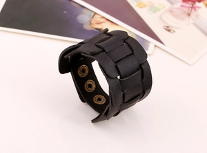Detail of vintage black braided wide leather bracelet with adjustable bronze snap buttons