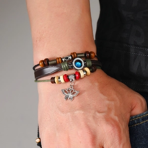 Detail of layered leather bracelet with wooden beads and silver butterfly pendant
