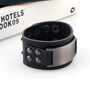 Détail macro du bracelet large en cuir noir pour homme avec plaque métal et rivets