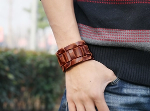 Close-up of wide braided dark brown genuine leather bracelet on a wrist in outdoor light