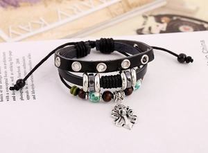 Dettaglio del bracciale punk multistrato in pelle con perline in legno e ciondolo a teschio