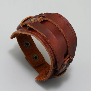 Macro detail of multi-layer brown leather bracelet with bronze snaps and stitching