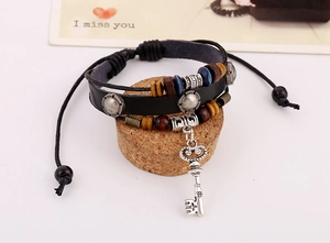 Close-up of multilayer leather bracelet featuring wooden beads and a key pendant charm