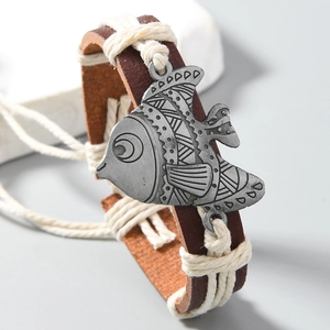 Close-up of a tribal silver fish charm on a braided brown PU leather bracelet