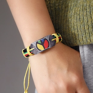 Handmade woven leather bracelet with red yellow green peace symbol on a green sweater