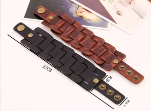 Detail of vintage wide braided leather bracelets in black and brown with adjustable snap buttons