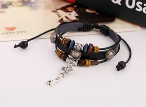 Close-up of multilayer leather bracelet featuring vintage key pendant and wooden beads