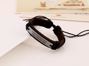 Macro detail of retro leather bracelet with engraved inspirational quote metal plate