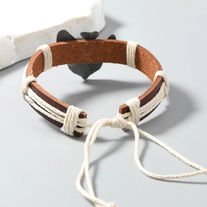 Detail of hand-woven leather owl bracelet with adjustable cords on a minimalist stone