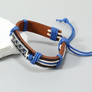 Detail of handmade leather bracelet with turtle charm and blue woven rope on stones