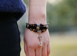 Detail of bohemian layered leather bracelet with wooden beads and vintage key pendant