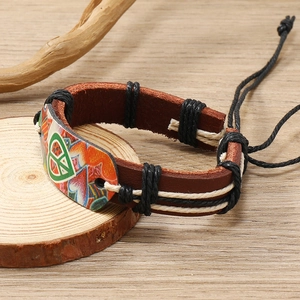 Vintage leather bracelet with colorful heart and peace sign on a rustic wooden background