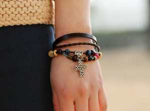 Detail of bohemian multilayer leather bracelet with colorful beads and silver cross pendant