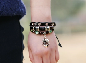 Dettaglio del bracciale punk multistrato in pelle con teschio d'argento e perline