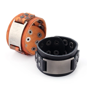 Détail de bracelets larges en cuir punk avec plaques métalliques et boutons pressions
