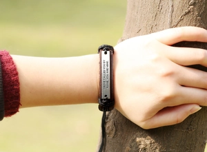 Detail of vintage leather bracelet with metal plate featuring engraved religious quote