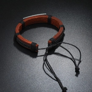 Bracelet en cuir tressé vintage avec plaque en métal argenté sur fond noir texturé