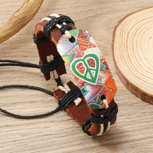 Detail of handmade leather bracelet with colorful heart peace sign on wooden surface