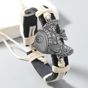 Macro shot of handcrafted leather wrap bracelet with vintage alloy fish pendant detail
