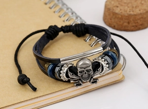 Macro detail of multi-layer leather bracelet with silver skull and cross-swords charms
