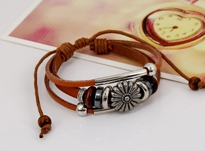 Detail of multilayer leather bracelet with sunflower charm and wooden beads on a gift card