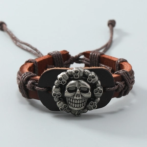 Vista macro del bracciale in pelle intrecciata con teschi argentati e chiusura regolabile