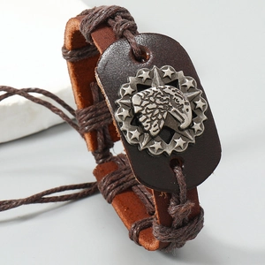 Macro shot of silver eagle head emblem on hand-woven brown leather punk bracelet