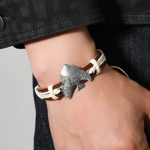 Handmade woven PU leather bracelet with vintage silver-tone metal bird charm on a wrist