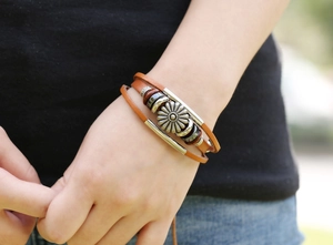 Close-up of multilayer leather bracelet with retro silver sunflower metal charm and beads