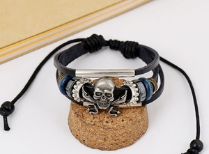 Detail of layered leather bracelet featuring vintage silver skull and crossbones charm