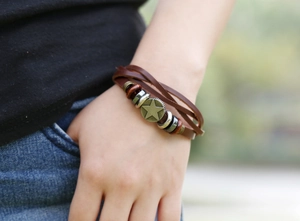 Detail of multilayer leather bracelet featuring a bronze star charm and wooden beads