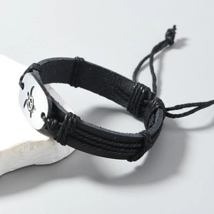 Close-up of braided leather bracelet with silver turtle and peace sign metal plaque