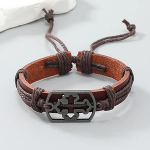 Macro detail of brown braided leather bracelet with vintage metal cross ornament