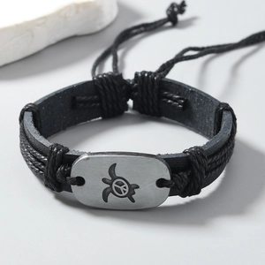 Detail of vintage braided leather bracelet with sea turtle peace sign metal plate
