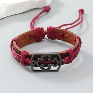 Detailed macro view of woven brown leather bracelet with silver floral metal charm