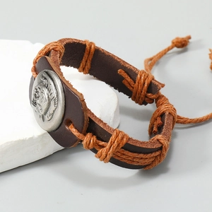 Detail of handmade braided leather bracelet with embossed silver tribal emblem