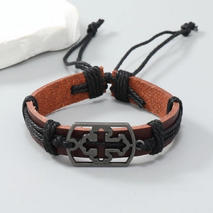 Detail of vintage brown leather bracelet with Celtic knot metal plaque and braided edges