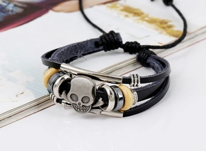Close-up of leather braided bracelet featuring a silver skull charm and wooden beads