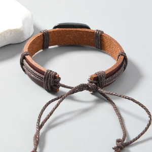 Detail of vintage brown leather bracelet with woven rope and adjustable knot closure
