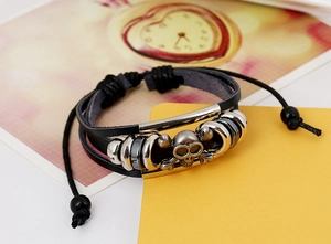 Dettaglio del bracciale multistrato in pelle con teschio e cordino intrecciato regolabile