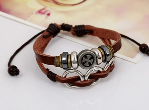 Detail of multi-layer leather bracelet featuring metal beads and a vintage cross charm