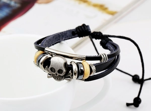 Detail of multi-layer braided leather bracelet with vintage alloy skull and yellow beads