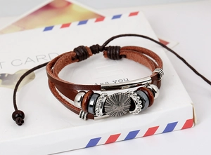 Detail of multilayer brown leather bracelet with vintage sunburst charm and adjustable cord