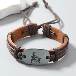 Detail of vintage brown leather bracelet featuring a silver sea turtle peace sign charm