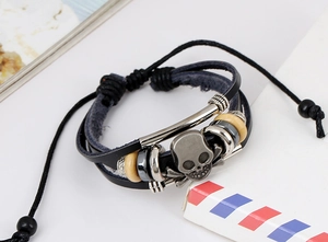 Macro detail of multi-layer leather bracelet with skull charm and wooden beads