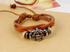 Macro shot of brown braided leather bracelet with vintage silver skull and wood beads