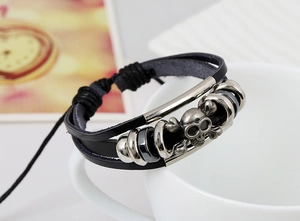 Dettaglio del bracciale punk multistrato in pelle con teschio d'argento e perline metalliche